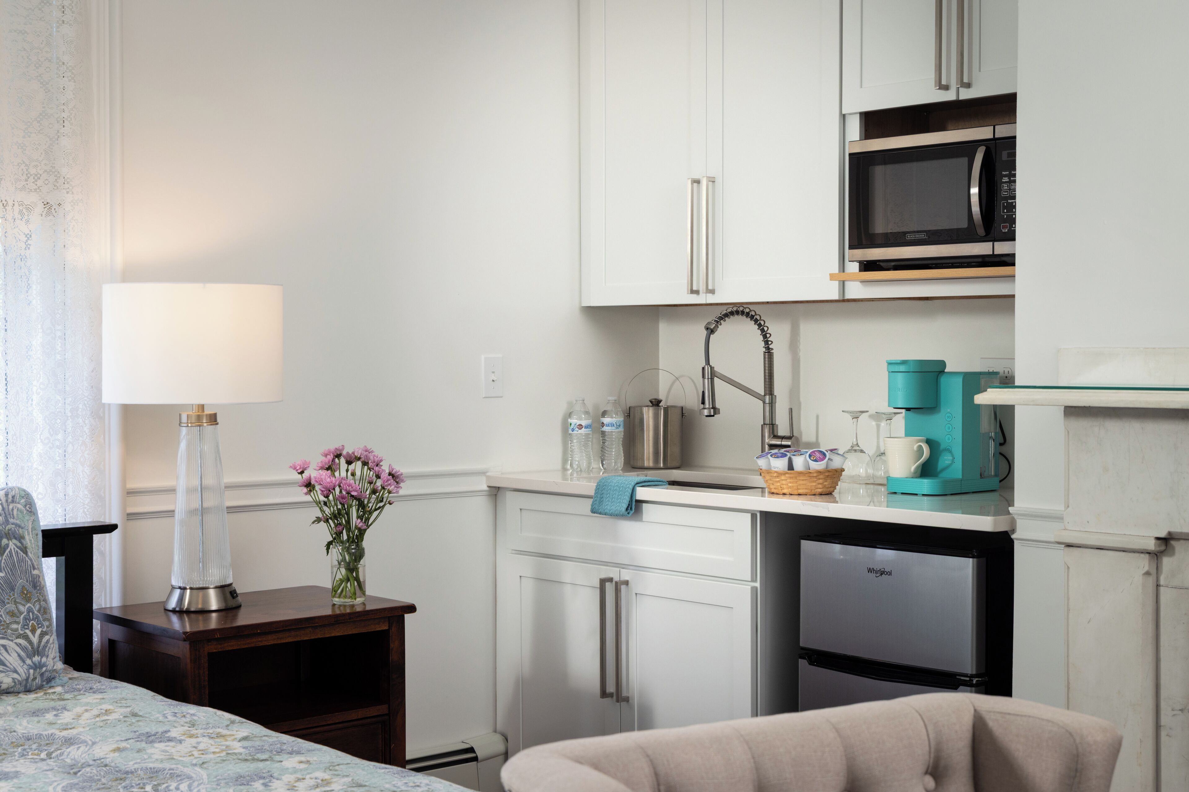 Una cocina moderna con armarios blancos, un microondas, una cafetera y un refrigerador.