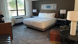 A hotel room with a large bed, two bedside tables with lamps, a desk, a chair, and a small table. - Grand Casino Mille Lacs Hotel (Onamia)