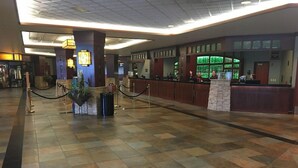 A spacious lobby with a check-in counter, a reception desk, and a seating area with a potted plant. - Grand Casino Mille Lacs Hotel (Onamia)