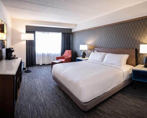 Habitación de hotel con una cama grande, un escritorio, una silla y un televisor.