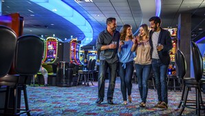 Un gruppo di persone in un ambiente interno ben illuminato, con cabinati arcade e posti a sedere.
