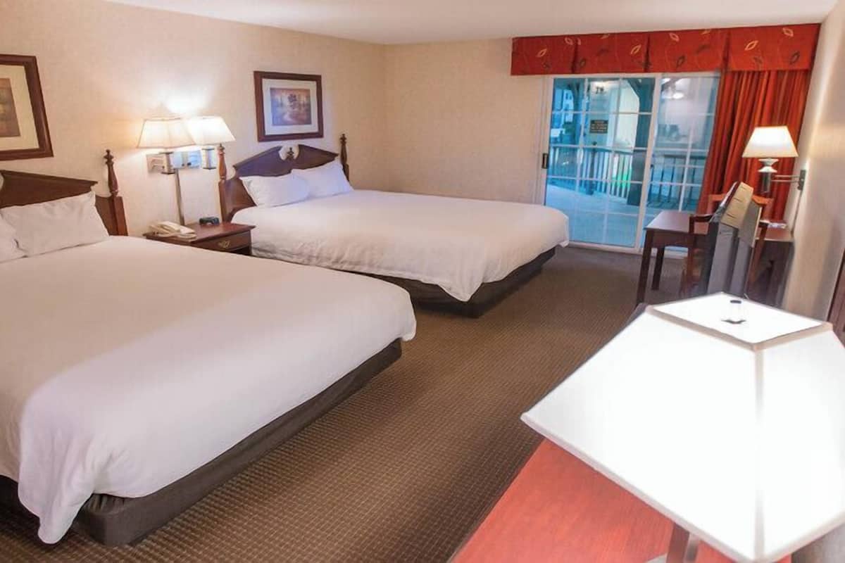Ein Hotelzimmer mit zwei Betten, einem Schreibtisch und einem Stuhl.