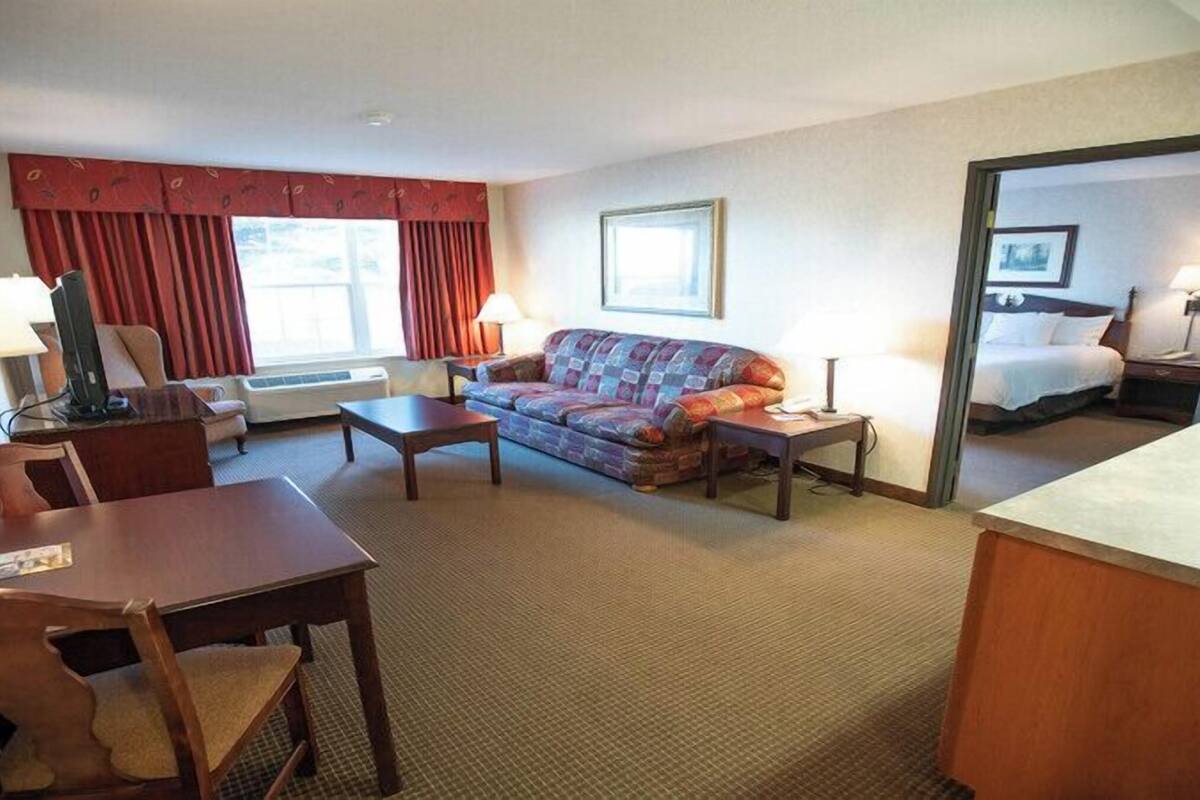 Ein Hotelzimmer mit Sofa, einem kleinen Tisch, einem Schreibtisch, einem Stuhl, einem Bett und einem Spiegel.