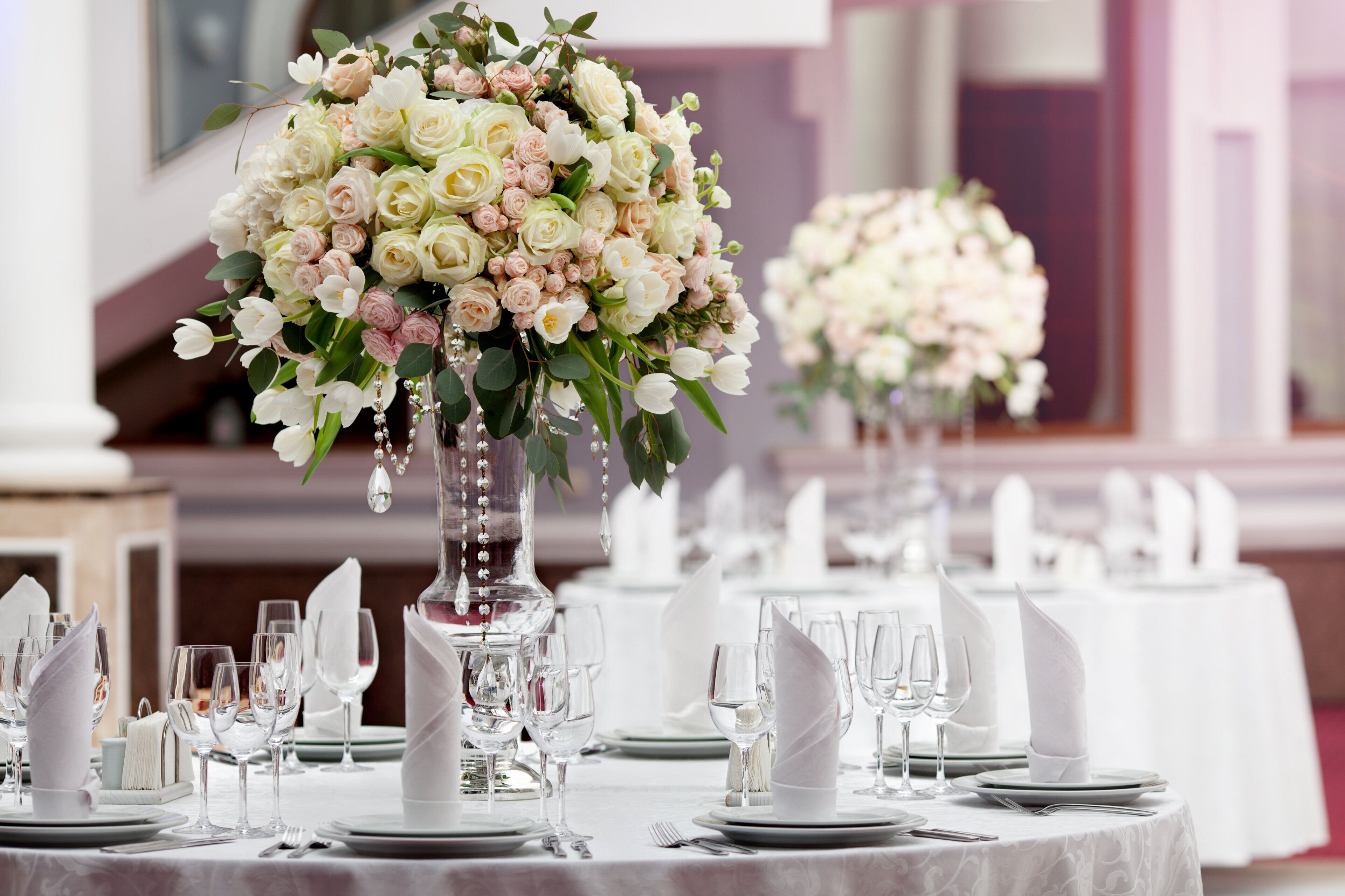 A banquet table set with white tablecloths, glassware, and folded napkins.