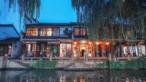 Un edificio chino tradicional con su reflejo en el agua, que presenta una escalera de piedra que conduce a la entrada.