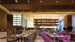 Un restaurante moderno con techo alto, asientos escalonados y una zona de bar central.