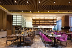 A modern restaurant with a high ceiling, tiered seating, and a central bar area. - Crowne Plaza Kunshan by IHG (Suzhou)