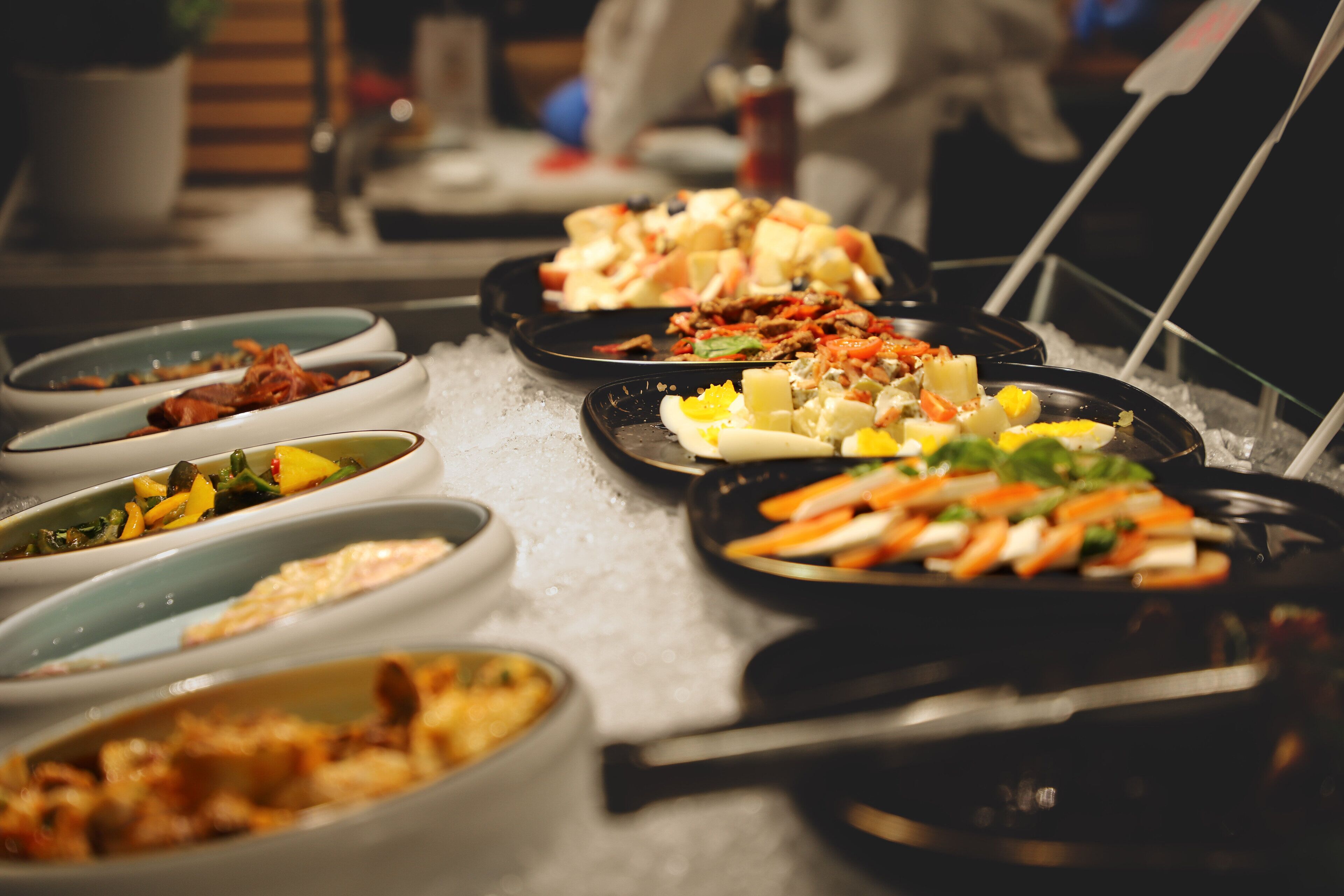 A buffet with various dishes on a bed of ice.