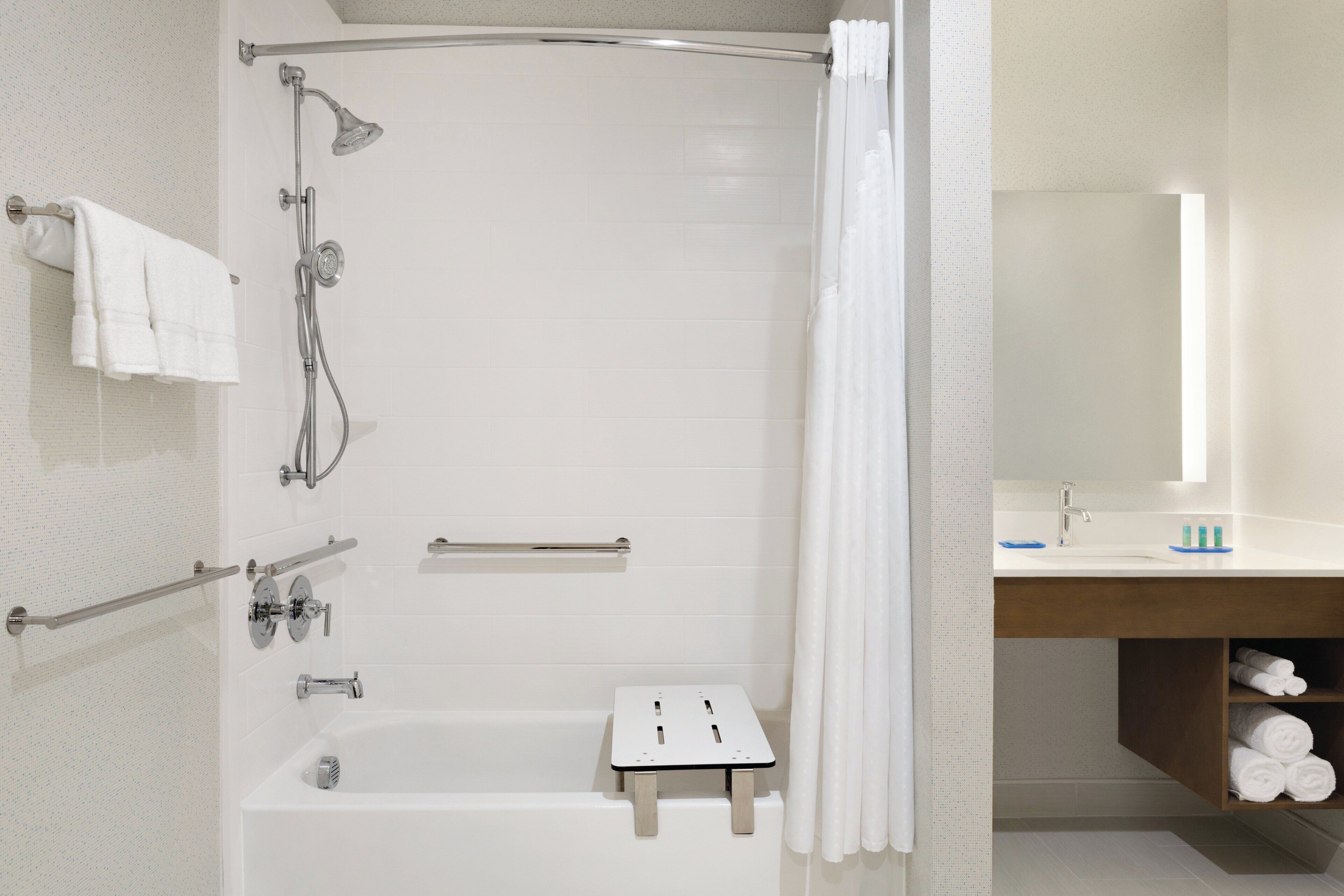 A modern bathroom with a shower, a bathtub, a towel rack, and a vanity with a mirror.