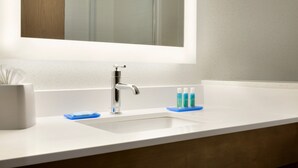 Ein Badezimmer mit einem weißen Waschbecken, einem Spiegel darüber und einer Holzausstattung.