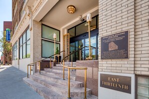 Une entrée d’immeuble avec une enseigne indiquant « EAST THIRTEENTH » et une plaque commémorative portant les inscriptions « INTER-STATE BUILDING 1914-1915 ».