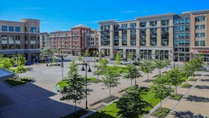 Una plaza urbana moderna con una rotonda central, rodeada de edificios de varios pisos con locales comerciales.