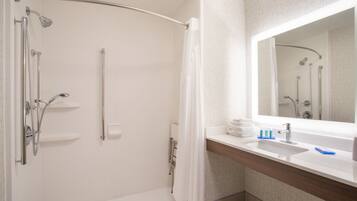 A modern bathroom with a shower, a sink, and a mirror.