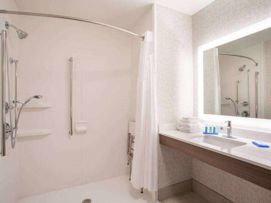 A modern bathroom with a shower, a sink, and a mirror.