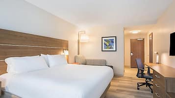 Una habitación de hotel con una cama grande, un escritorio con una silla, un televisor de pantalla plana y un cuadro en la pared.