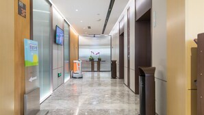 Un couloir d’hôtel avec un comptoir de réception, une poubelle et un distributeur automatique.