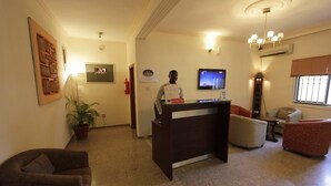 A reception area with a desk, chairs, a television, and a potted plant.