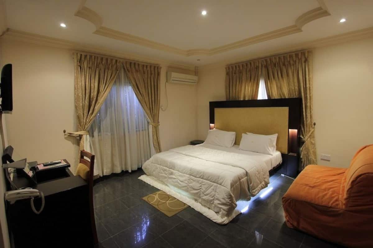 Ein Hotelzimmer mit einem großen Bett, einem Schreibtisch mit Telefon und einem Sessel.