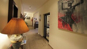 A hallway with a lamp, a painting, and a reception desk.