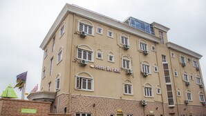 Un hotel de varios pisos con fachada color crema, múltiples balcones y un letrero que dice "Hotel Bel Ami".