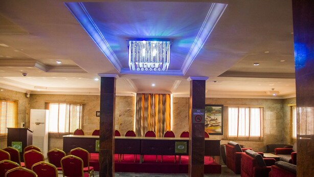 Un salón de conferencias con una araña, sillas rojas, una larga mesa y un cartel de 'No Smoking'.