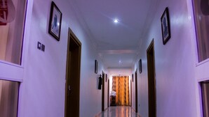 Pasillo de hotel con puertas a ambos lados, cuadros en las paredes y un piso de baldosas reflectantes.