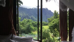 Una habitación con un amplio ventanal que da a un valle exuberante y montañas.