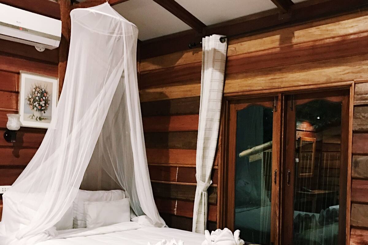 Una habitación de cabaña de madera con una cama con dosel, una ventana con vistas y techo de madera.