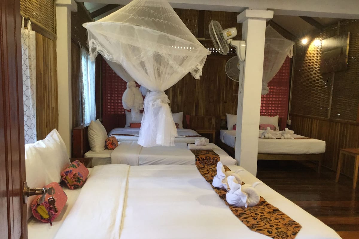 Una habitación de hotel con una cama grande, un área de descanso y un ventilador.
