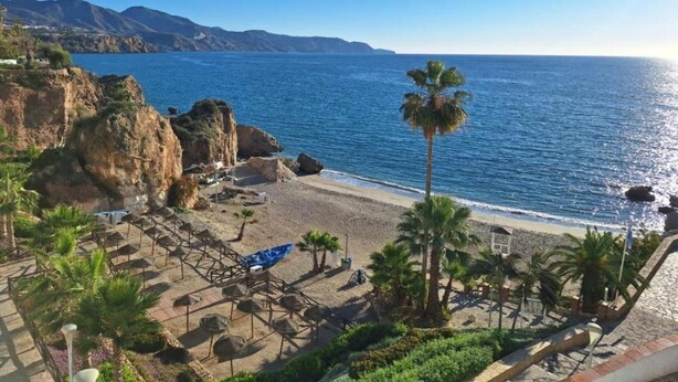 A beach with a rocky cliff, palm trees, and a clear blue sea. - Belvilla by OYO Francisco (Frigiliana)