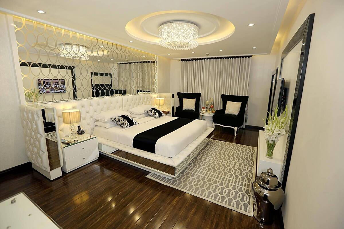 Une chambre d’hôtel moderne avec un grand lit, un lustre, un miroir et une table de chevet.