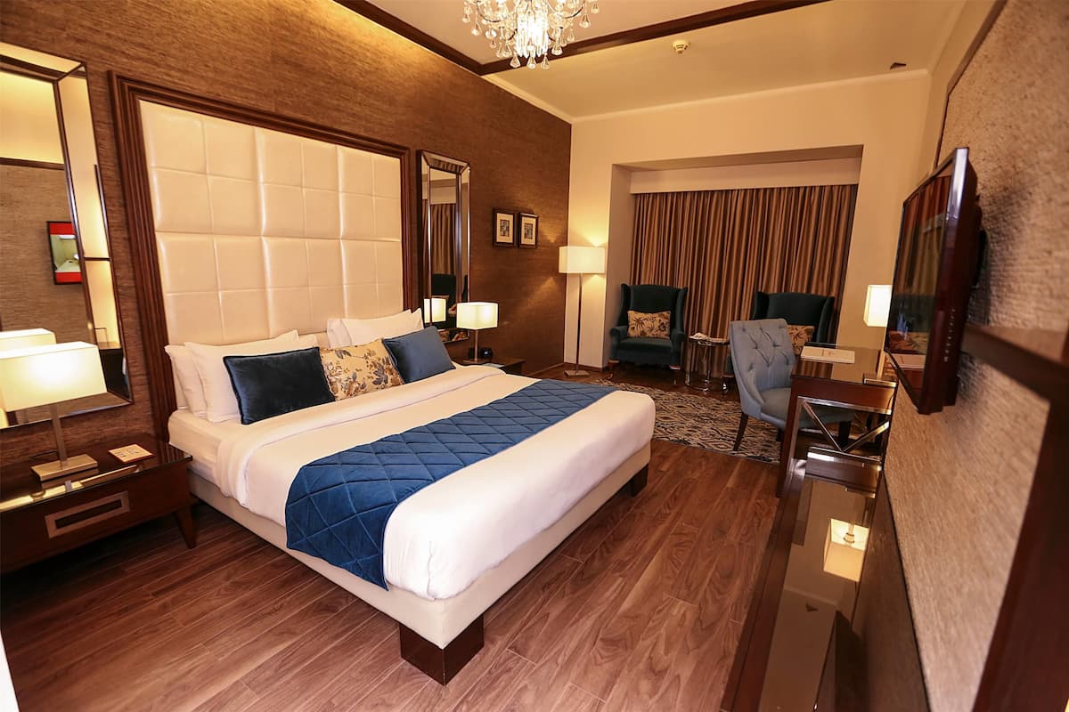 Une chambre d’hôtel avec un grand lit, un bureau, une chaise et un téléviseur.