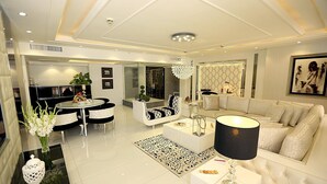 A modern living room with a sofa, a dining table, and a chandelier. - Ramada by Wyndham Multan (Multan)