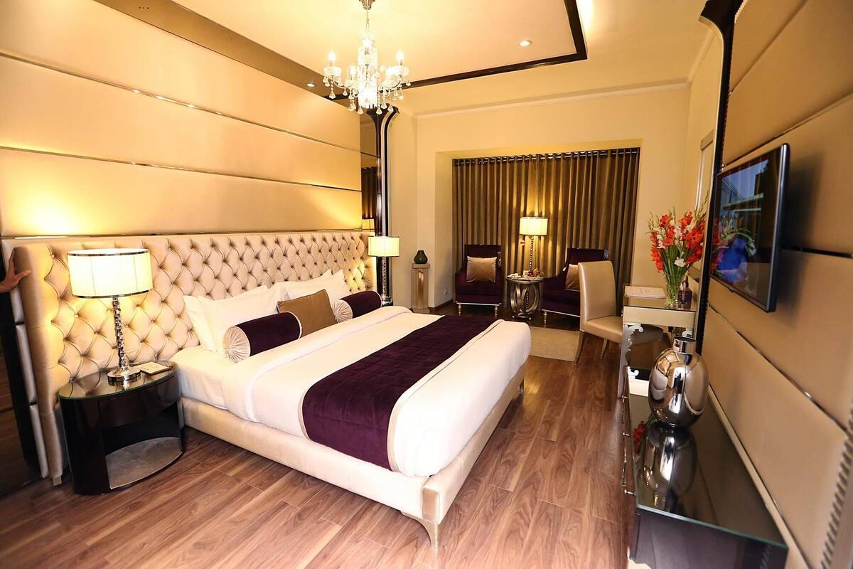 Une chambre d’hôtel avec un grand lit, un lustre, un bureau et un téléviseur.