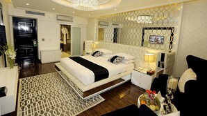 A modern hotel room with a large bed, bedside tables, a chandelier, and a television. - Ramada by Wyndham Multan (Multan)