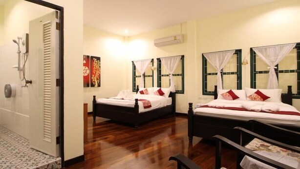 A hotel room with two beds, a shower area, and a bathroom. - Srisomboon Hostel (Trang)