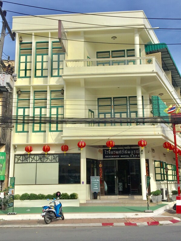 A two-story building with a balcony, a sign for 'Srisomboon Hostel', and a parked scooter in front. - Srisomboon Hostel (Trang)
