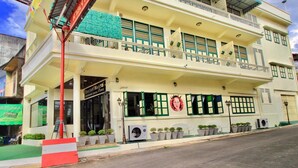 A multi-story building with a balcony, air conditioning units, and potted plants. - Srisomboon Hostel (Trang)