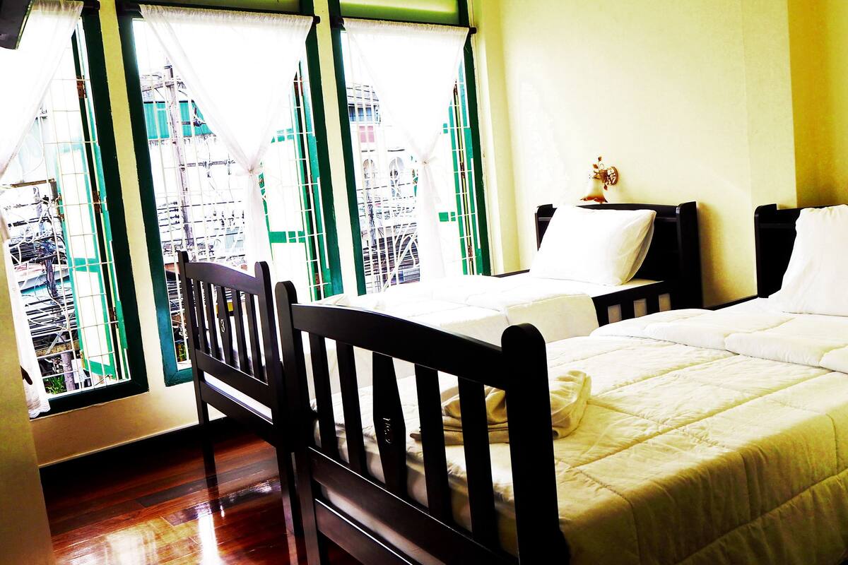 A room with a bed, a chair, and a window with a view of buildings.