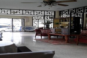 A spacious living area with a ceiling fan, a dining table, and a sofa. - Srisomboon Hostel (Trang)