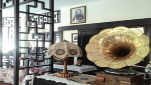 A room with a vintage gramophone, a patterned lamp, and a decorative screen. - Srisomboon Hostel (Trang)