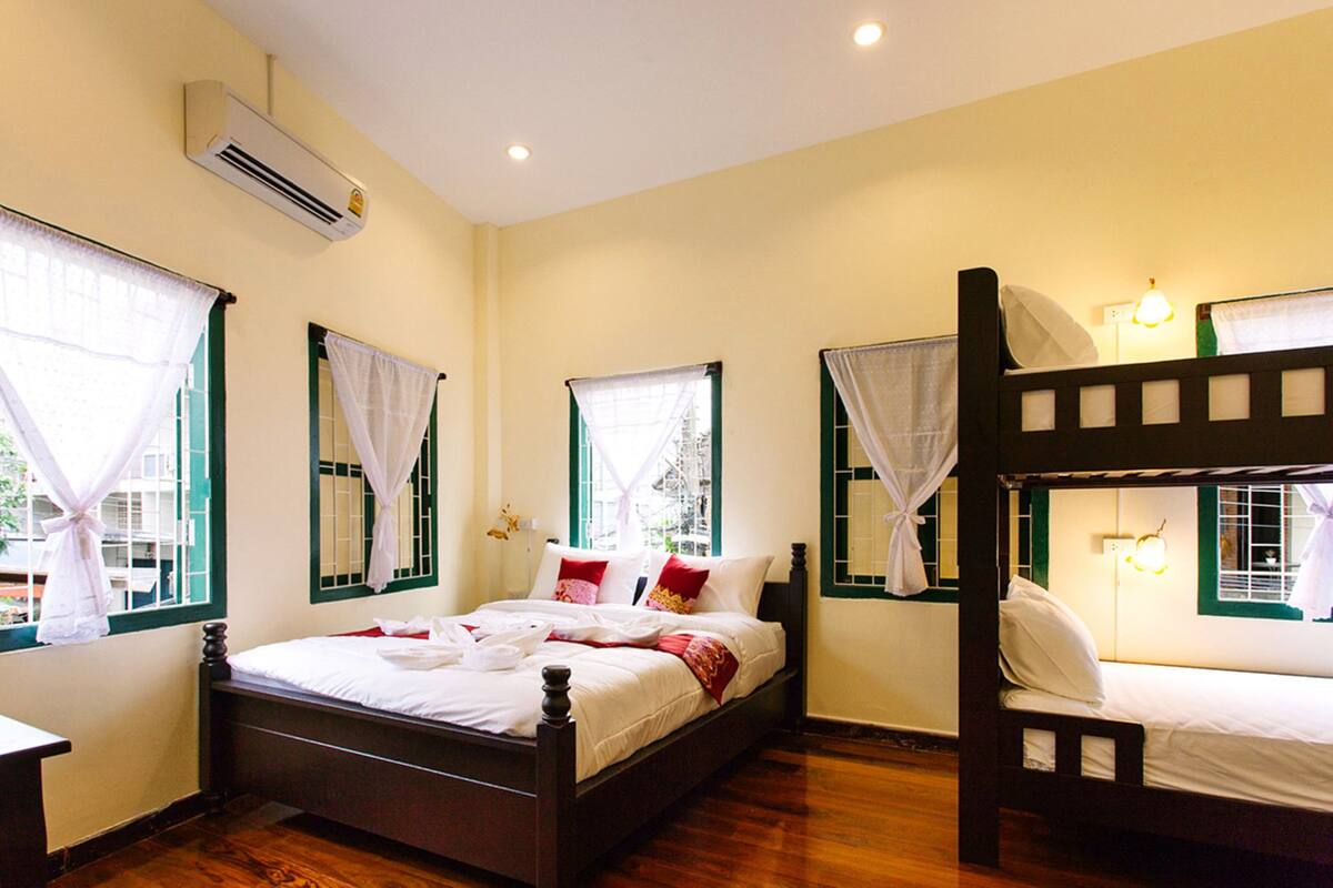 A room with a wooden bed, a bunk bed, and a window with a curtain.