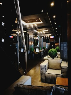 A modern interior with a staircase, seating area, and decorative lighting.