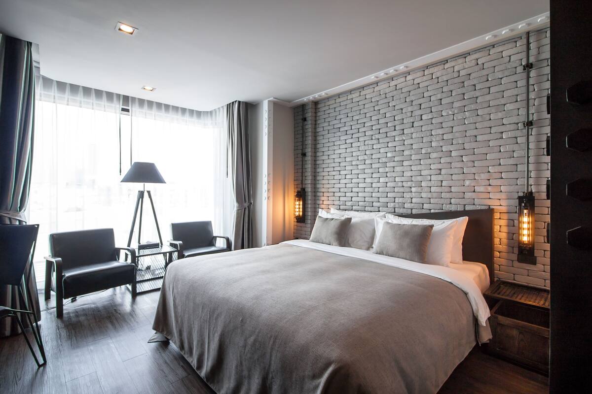 A modern hotel room with a large bed, a desk, and a chair.