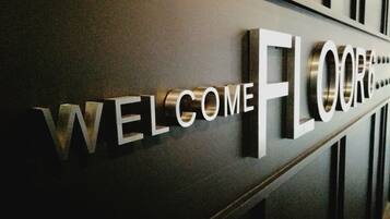 A welcome sign with the text "WELCOME FLOOR" on a dark wall.