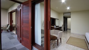 A spacious room with a large sliding door, a sofa, a small round table, and a television. - Byasa Ubud (Ubud)