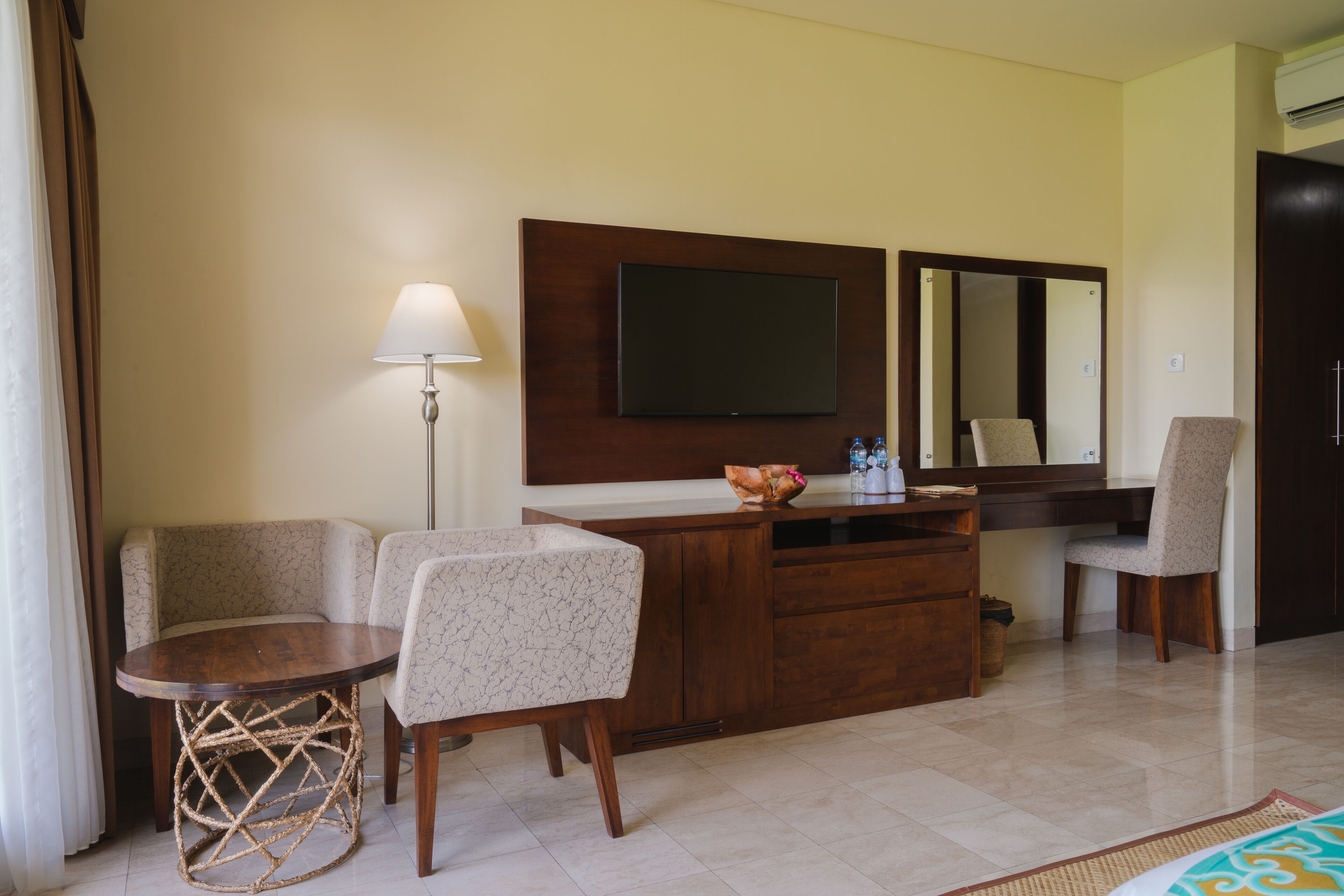 Habitación de hotel con un escritorio de madera, dos sillas, un televisor, un espejo y un armario.