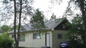 A single-story house with a gabled roof, a front door, and a small front yard. - Canora Cozy Cottage (Canora)