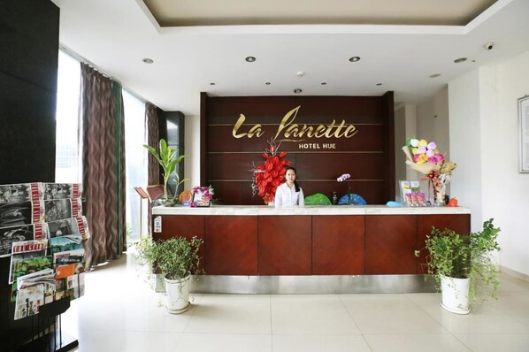 A hotel reception desk with a sign reading "La Janette Hotel Hue".