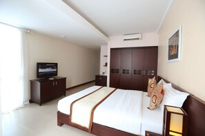 A hotel room with a large bed, a television, a wardrobe, and a wall-mounted air conditioner.